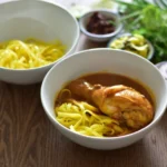 ข้าวซอยไก่ใส่เส้นกรอบและเส้นลวก พร้อมพริกผัดน้ำมัน หอมแดงซอย และผักกาดดอง